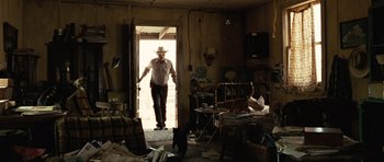 Movie still from “No Country for Old Men” (2007), directed by Joel Coen – A man wearing a cowboy hat standing in the doorway of a room; Wide shot, Low angle