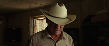 Movie still from “No Country for Old Men” (2007), directed by Joel Coen – A man wearing a white cowboy hat and a beige shirt; Close Up shot, Over the shoulder angle