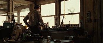 Movie still from “No Country for Old Men” (2007), directed by Joel Coen – A man standing in front of a window in a kitchen; Medium shot, Low angle