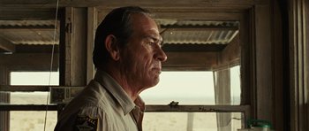 Movie still from “No Country for Old Men” (2007), directed by Joel Coen – An older man looking out of a window; Close Up shot, Low angle