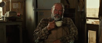 Movie still from “No Country for Old Men” (2007), directed by Joel Coen – An older man holding a coffee cup in a kitchen; Close Up shot, Low angle