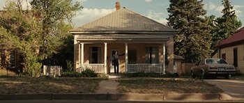 Movie still from “No Country for Old Men” (2007), directed by Joel Coen – A man standing in front of an old house; Extreme Wide shot, Low angle