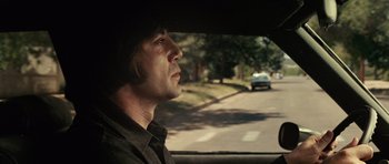 Movie still from “No Country for Old Men” (2007), directed by Joel Coen – A man sitting in the passenger seat of a car looking out the window; Close Up shot, Over the shoulder angle