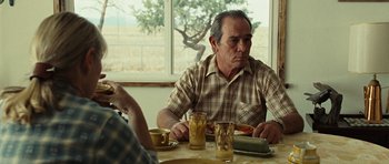 Movie still from “No Country for Old Men” (2007), directed by Joel Coen – A man sitting at a table with a plate in front of him; Medium shot, Over the shoulder angle