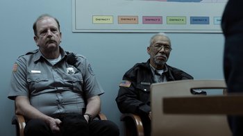 Movie still from “No Good Deed” (2014), directed by Sam Miller – Two police officers sitting next to each other in a room; Medium shot, Over the shoulder angle