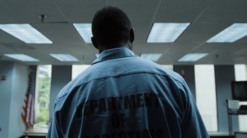 Movie still from “No Good Deed” (2014), directed by Sam Miller – The back of a man's shirt with the department of corrections written on it; Medium shot, Low angle