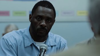 Movie still from “No Good Deed” (2014), directed by Sam Miller – A man in a blue shirt is sitting in front of a microphone; Close Up shot, Over the shoulder angle