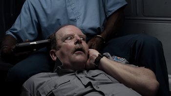 Movie still from “No Good Deed” (2014), directed by Sam Miller – A police officer laying on the ground talking on a cell phone; Close Up shot, High angle