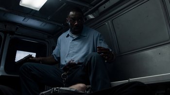 Movie still from “No Good Deed” (2014), directed by Sam Miller – A man sitting on the back of a vehicle; Medium shot, High angle
