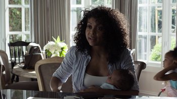 Movie still from “No Good Deed” (2014), directed by Sam Miller – A woman sitting at a table holding a baby; Medium shot, Over the shoulder angle