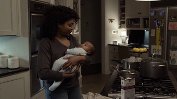 Movie still from “No Good Deed” (2014), directed by Sam Miller – A woman holding a baby in her arms in a kitchen; Medium shot, Over the shoulder angle