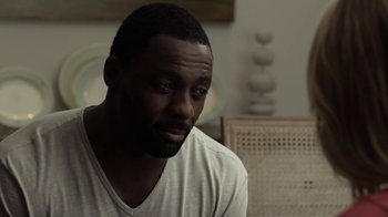 Movie still from “No Good Deed” (2014), directed by Sam Miller – A man sitting in front of a chair in a living room; Close Up shot, Over the shoulder angle