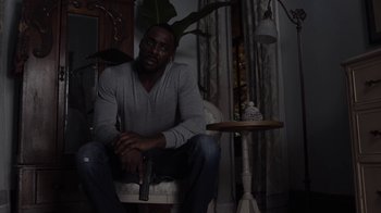 Movie still from “No Good Deed” (2014), directed by Sam Miller – A man sitting in a chair holding a remote control; Medium shot, High angle