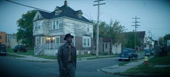 Movie still from “No Sudden Move” (2021), directed by Steven Soderbergh – A man walking down the street wearing a hat; Wide shot, Over the shoulder angle