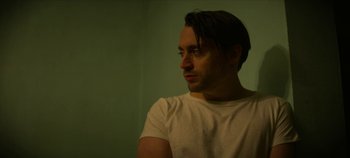 Movie still from “No Sudden Move” (2021), directed by Steven Soderbergh – A person wearing a white t - shirt; Close Up shot, Low angle