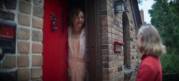 Movie still from “No Sudden Move” (2021), directed by Steven Soderbergh – A woman standing in front of a red door; Medium shot, Low angle