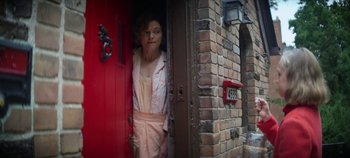 Movie still from “No Sudden Move” (2021), directed by Steven Soderbergh – A woman standing in front of a red door; Medium shot, Low angle