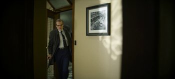 Movie still from “No Sudden Move” (2021), directed by Steven Soderbergh – A man in a suit and tie standing in front of a door; Medium shot, Low angle