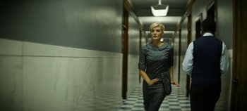 Movie still from “No Sudden Move” (2021), directed by Steven Soderbergh – A woman walking down a hall way in a building; Medium shot, Low angle