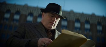 Movie still from “No Sudden Move” (2021), directed by Steven Soderbergh – A man wearing a hat and a suit looking down at a piece of paper; Close Up shot, Low angle