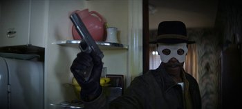 Movie still from “No Sudden Move” (2021), directed by Steven Soderbergh – A man holding a gun wearing a white mask; Close Up shot, Low angle
