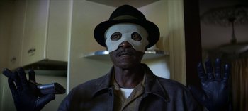 Movie still from “No Sudden Move” (2021), directed by Steven Soderbergh – A man wearing a mask and a hat; Close Up shot, Low angle