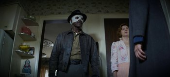 Movie still from “No Sudden Move” (2021), directed by Steven Soderbergh – A man wearing a mask standing next to a woman; Medium shot, Low angle