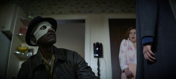 Movie still from “No Sudden Move” (2021), directed by Steven Soderbergh – A man with a blindfold and a woman in a doorway; Medium shot, Over the shoulder angle
