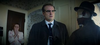 Movie still from “No Sudden Move” (2021), directed by Steven Soderbergh – A man in a suit and tie standing in a room; Close Up shot, Over the shoulder angle