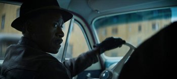 Movie still from “No Sudden Move” (2021), directed by Steven Soderbergh – A man in a hat is driving a car; Close Up shot, Over the shoulder angle