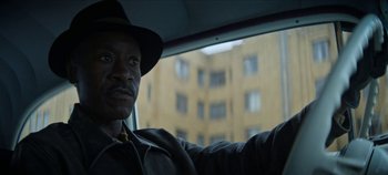 Movie still from “No Sudden Move” (2021), directed by Steven Soderbergh – A man sitting in the passenger seat of a car; Close Up shot, Low angle