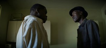 Movie still from “No Sudden Move” (2021), directed by Steven Soderbergh – Two men standing next to each other in a room; Close Up shot, Over the shoulder angle