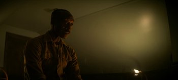 Movie still from “No Sudden Move” (2021), directed by Steven Soderbergh – A man standing in a room with a light shining on him; Close Up shot, Low angle