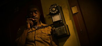 Movie still from “No Sudden Move” (2021), directed by Steven Soderbergh – A man holding a phone up to his ear; Close Up shot, High angle