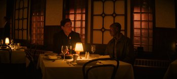 Movie still from “No Sudden Move” (2021), directed by Steven Soderbergh – Two men are sitting at a table in front of a lamp; Wide shot, High angle