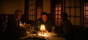 Movie still from “No Sudden Move” (2021), directed by Steven Soderbergh – A group of people sitting at a dinner table; Medium shot, Over the shoulder angle