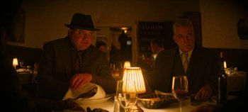 Movie still from “No Sudden Move” (2021), directed by Steven Soderbergh – A group of men sitting at a table in a restaurant; Medium shot, Over the shoulder angle