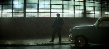 Movie still from “No Sudden Move” (2021), directed by Steven Soderbergh – A man walking down a street in the rain; Wide shot, Low angle