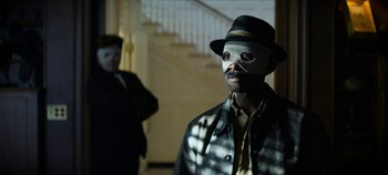Movie still from “No Sudden Move” (2021), directed by Steven Soderbergh – A man wearing a mask and a hat; Close Up shot, Low angle