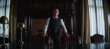 Movie still from “No Sudden Move” (2021), directed by Steven Soderbergh – A man standing in front of a table with a glass; Medium shot, Low angle