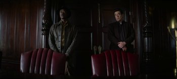 Movie still from “No Sudden Move” (2021), directed by Steven Soderbergh – Two men are sitting in front of a red door; Medium shot, Low angle