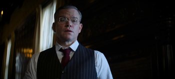 Movie still from “No Sudden Move” (2021), directed by Steven Soderbergh – A man in a suit and tie standing in front of a window; Close Up shot, Low angle
