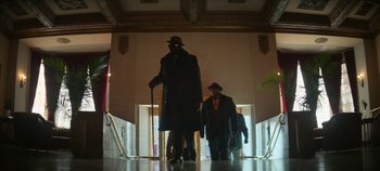 Movie still from “No Sudden Move” (2021), directed by Steven Soderbergh – Two men in suits and hats are walking down the hall way; Wide shot, Low angle