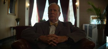 Movie still from “No Sudden Move” (2021), directed by Steven Soderbergh – An older man wearing a suit and a bow tie; Close Up shot, Low angle