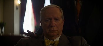 Movie still from “No Sudden Move” (2021), directed by Steven Soderbergh – An older man wearing a suit and a bow tie; Close Up shot, Low angle