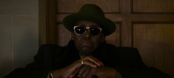 Movie still from “No Sudden Move” (2021), directed by Steven Soderbergh – A person wearing sunglasses and a hat; Close Up shot, Low angle