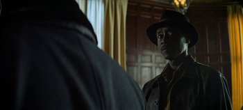 Movie still from “No Sudden Move” (2021), directed by Steven Soderbergh – A man wearing a hat looking into a mirror; Close Up shot, Over the shoulder angle