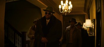 Movie still from “No Sudden Move” (2021), directed by Steven Soderbergh – A group of men standing next to each other in front of a chandelier; Medium shot, Low angle