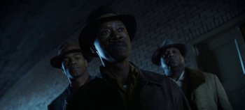 Movie still from “No Sudden Move” (2021), directed by Steven Soderbergh – A group of men standing next to each other in a dark room; Close Up shot, Low angle