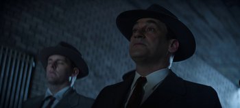 Movie still from “No Sudden Move” (2021), directed by Steven Soderbergh – A man in a suit and a hat is looking up; Medium shot, Low angle